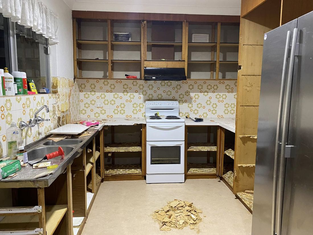 Kitchen before renovation — dated cabinetry being removed
