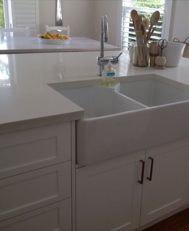 White shaker kitchen island with a double farmhouse butler's sink and stone benchtop
