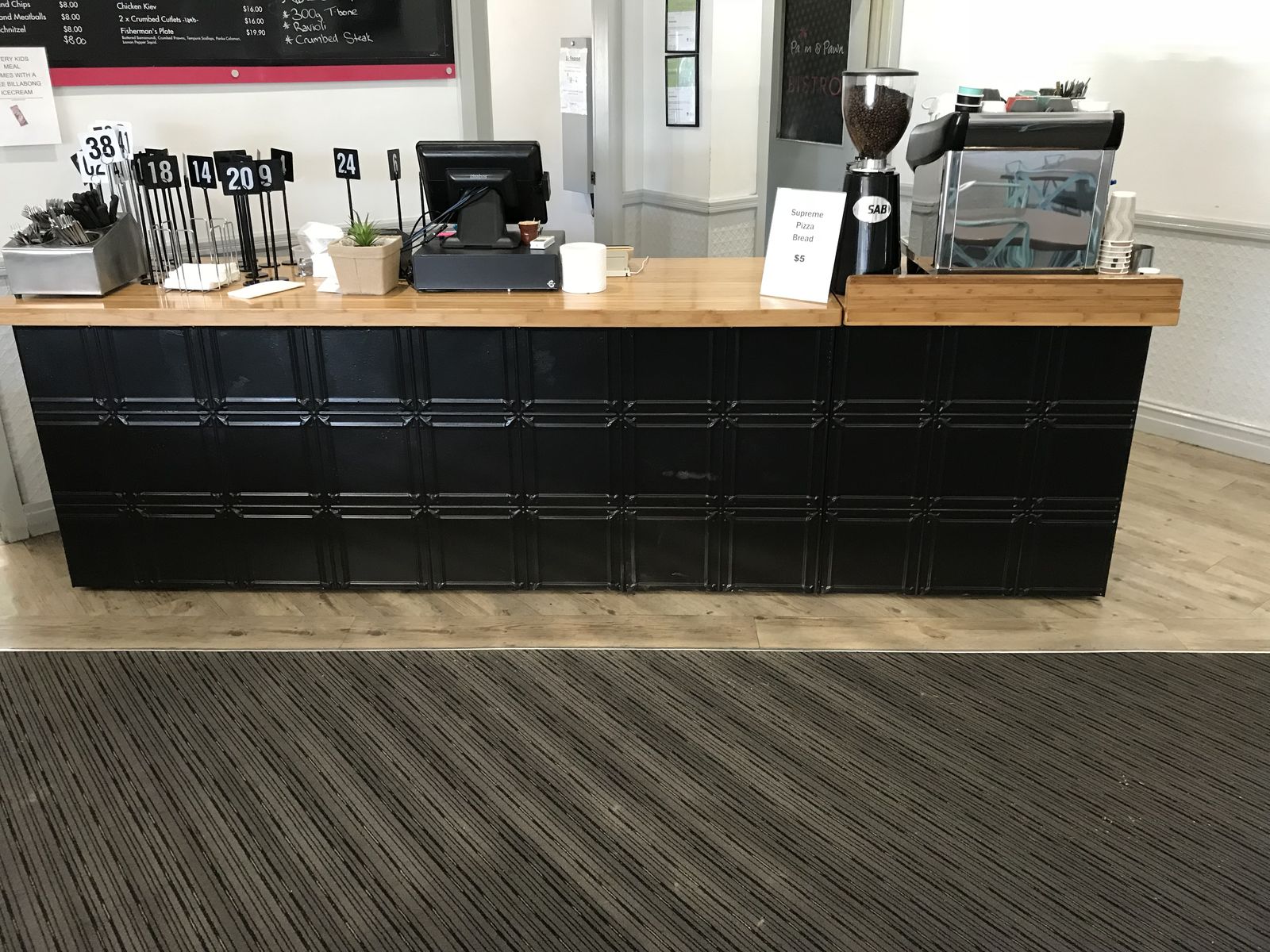 Café service counter with black cabinetry and timber benchtop
