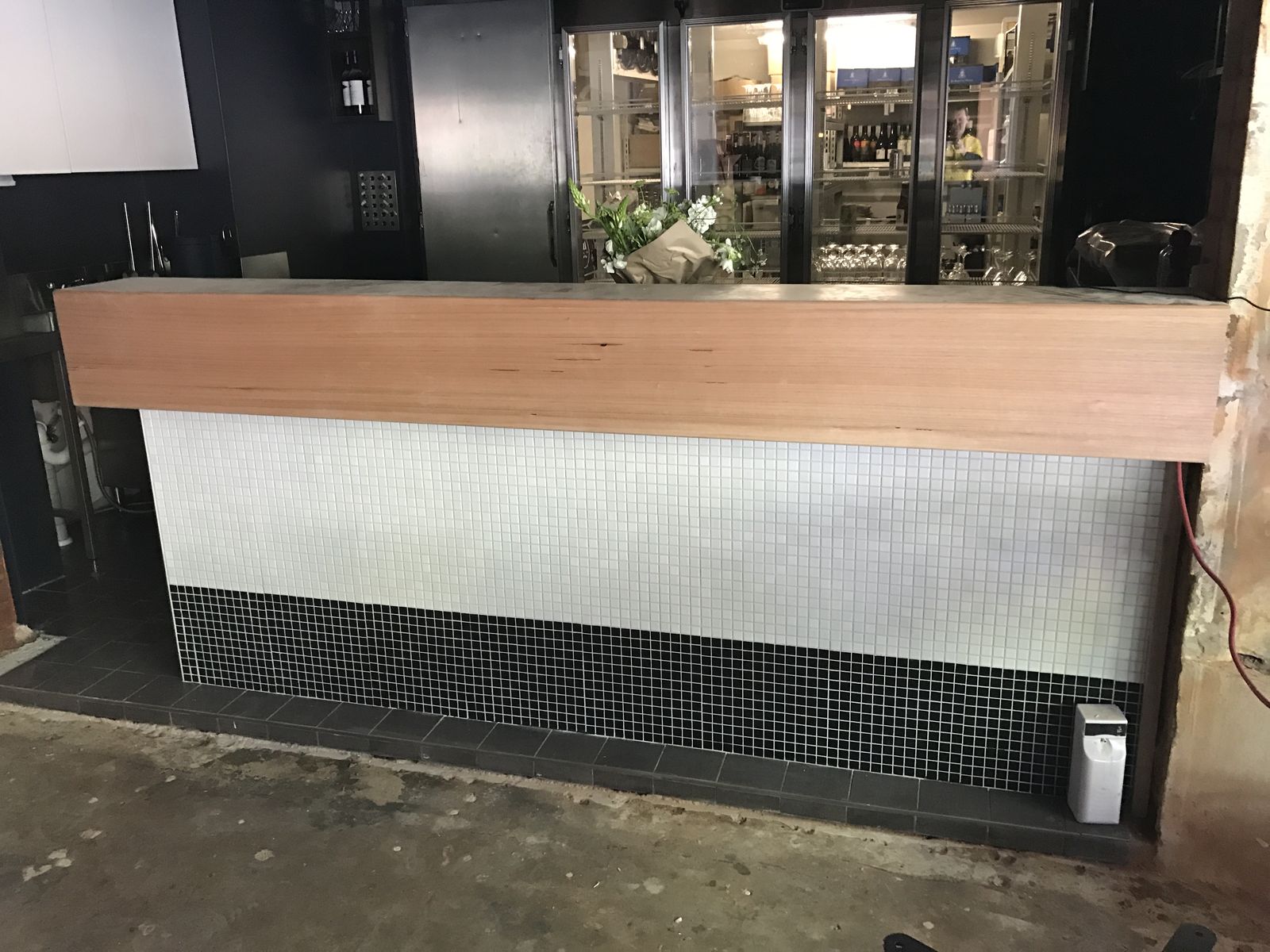 Timber-topped Hamptons-style bar with mosaic front in a venue