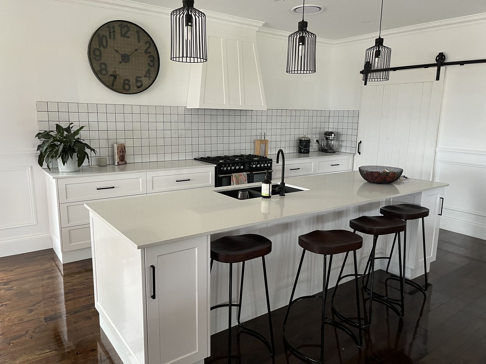 Classic white shaker kitchen with barn door, island and black bar stools