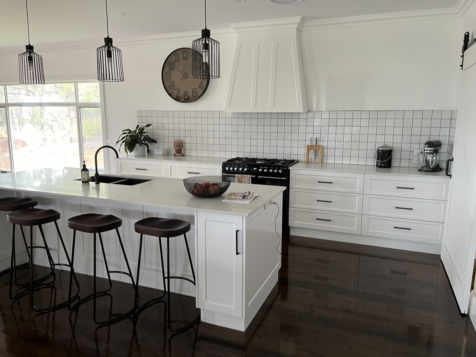 Shaker kitchen island with black bar stools and subway tile splashback