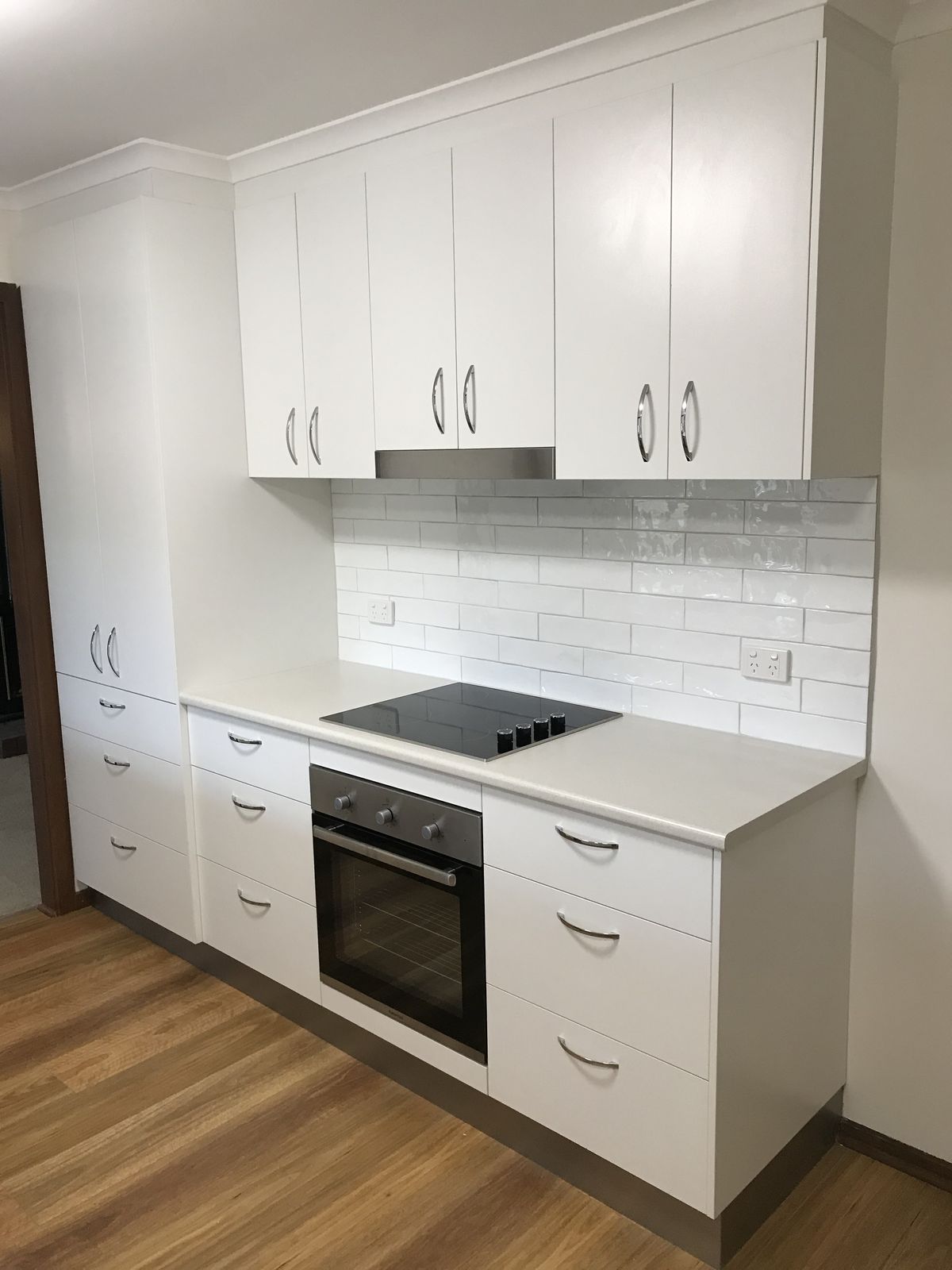Compact kitchen with white and timber cabinetry and integrated appliances