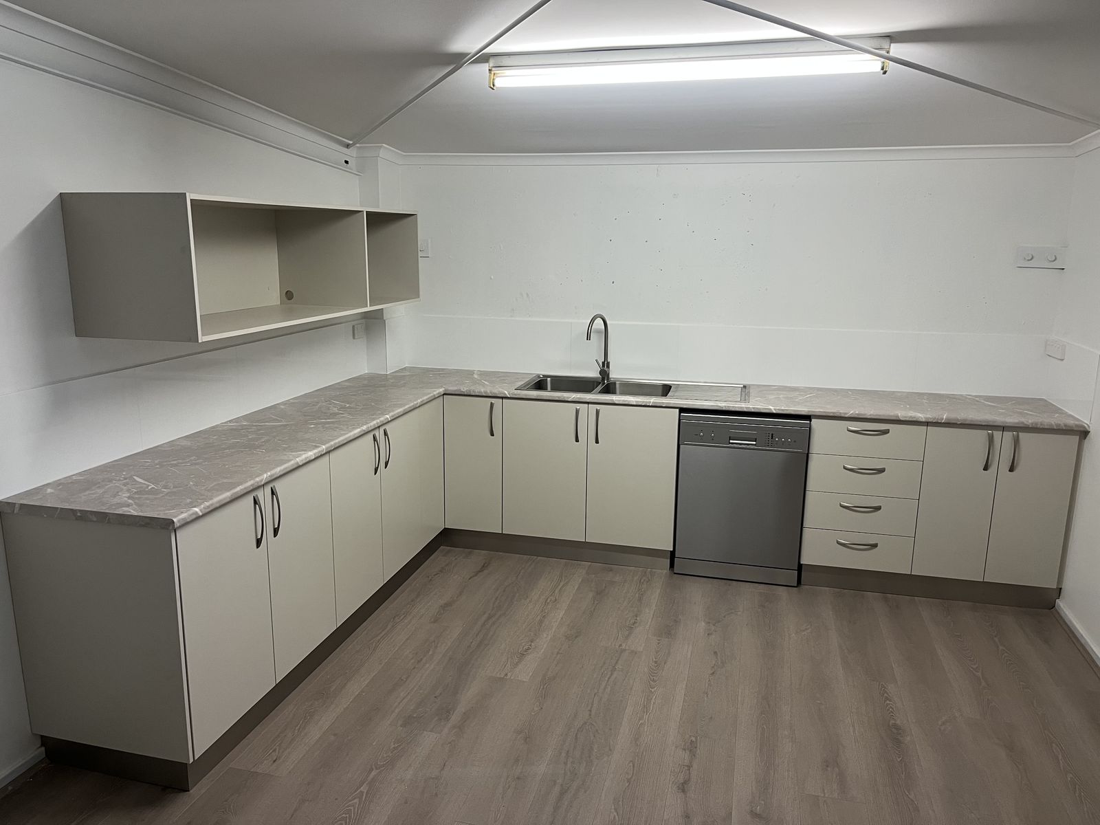L-shaped kitchen with white cabinetry, stone benchtops and timber-look floor