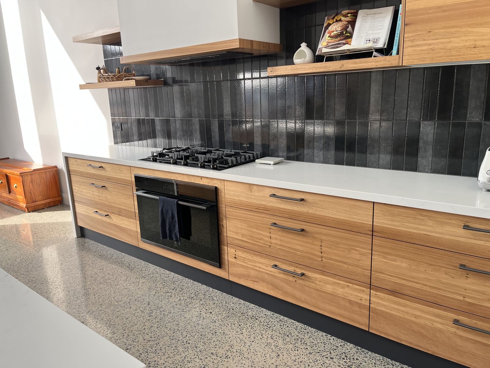 Open-plan white shaker kitchen with island bench and dark feature splashback