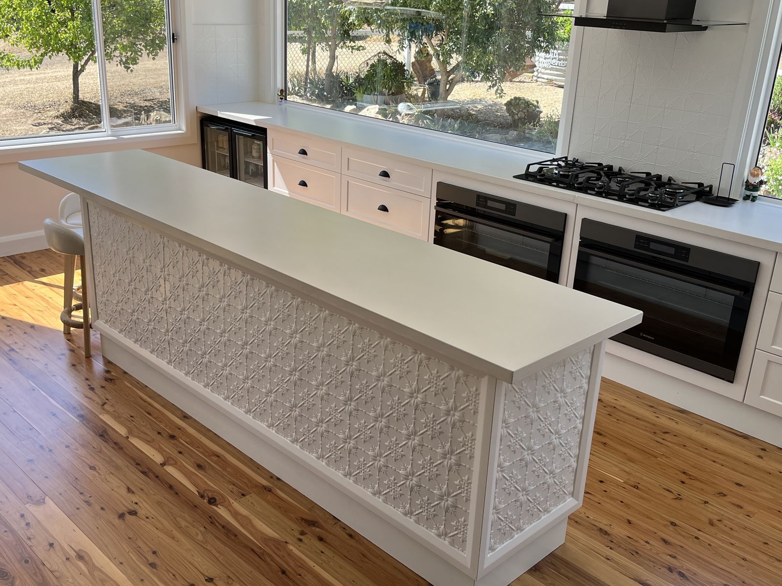Kitchen island with textured stone front and engineered stone benchtop