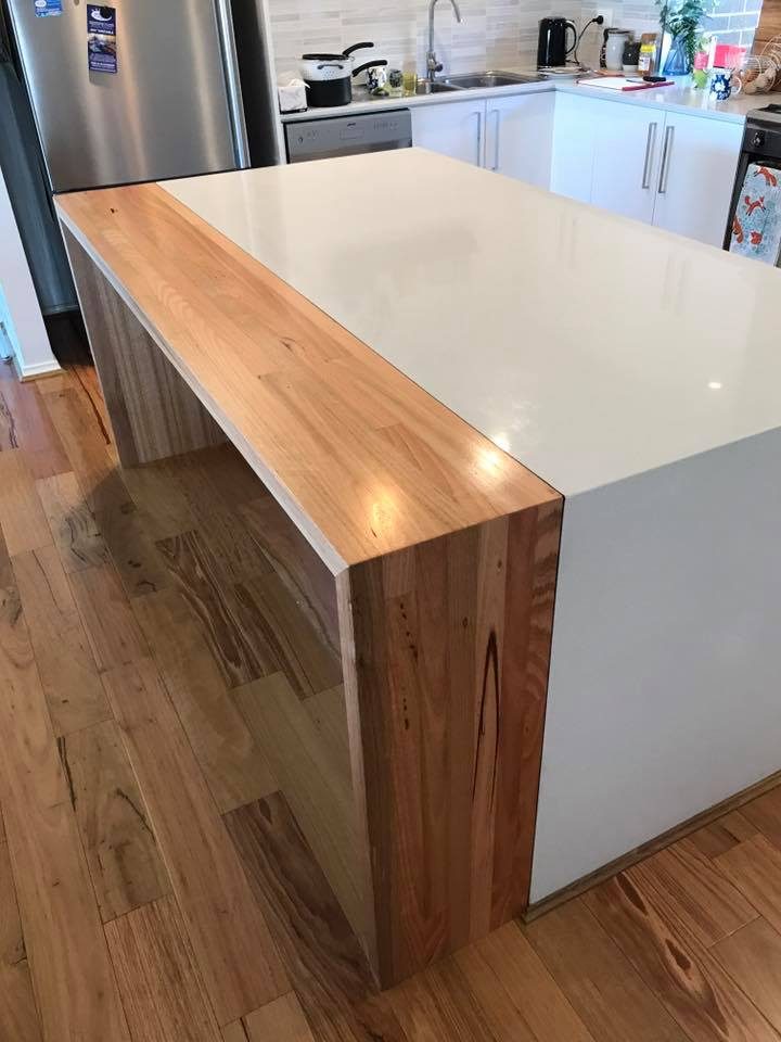Custom kitchen island with white benchtop and timber waterfall end