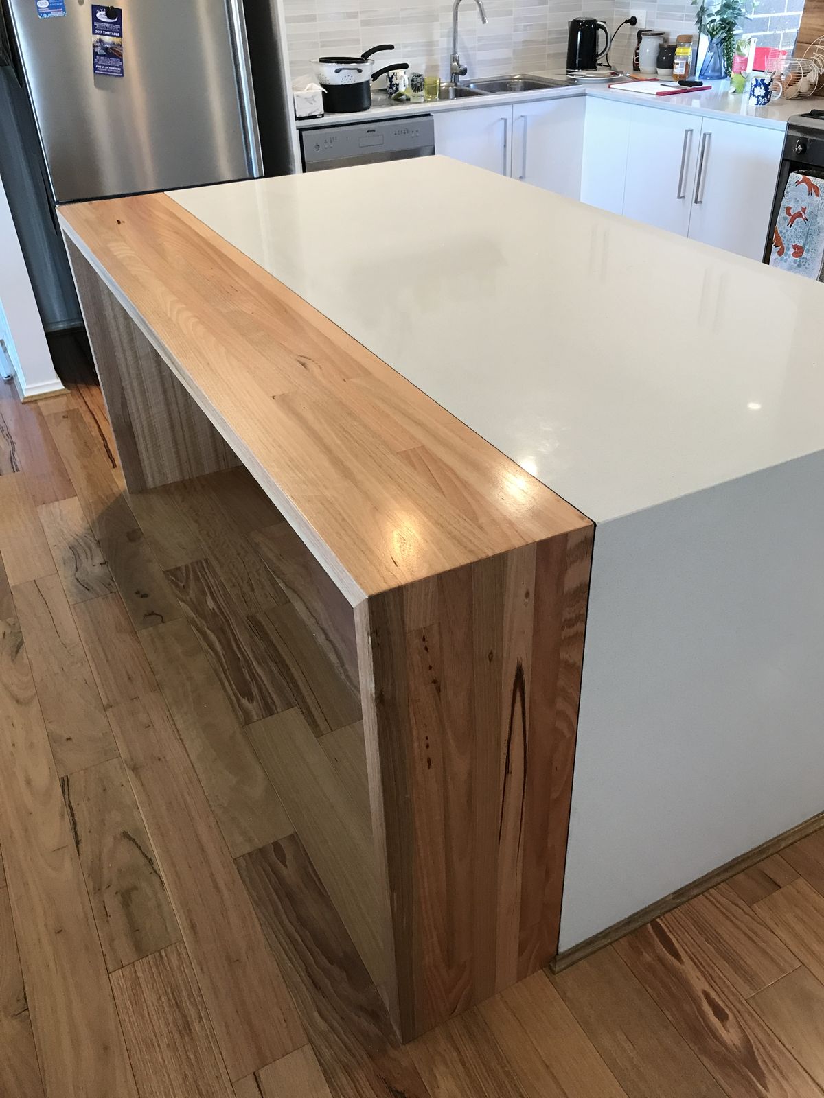 Custom island with white cabinetry and a solid timber waterfall benchtop