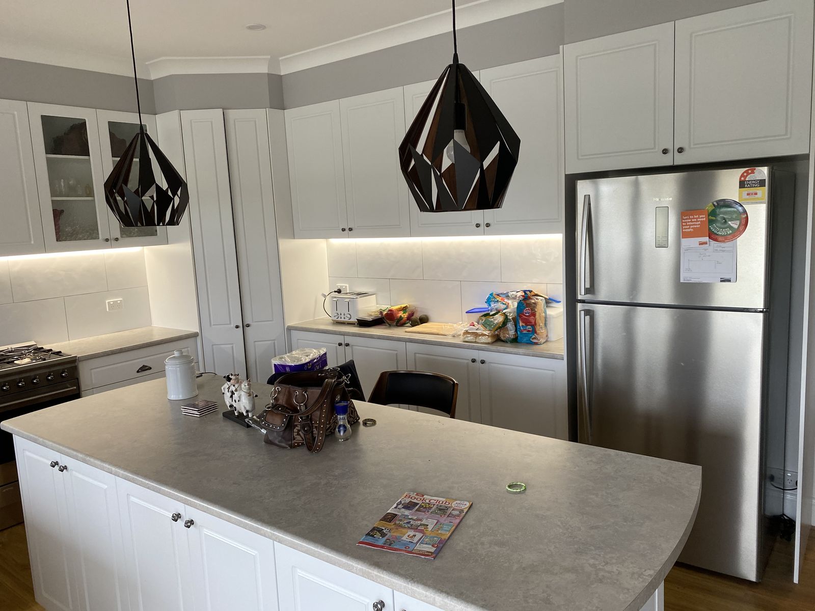 White shaker kitchen island with stone benchtop and geometric pendant lighting