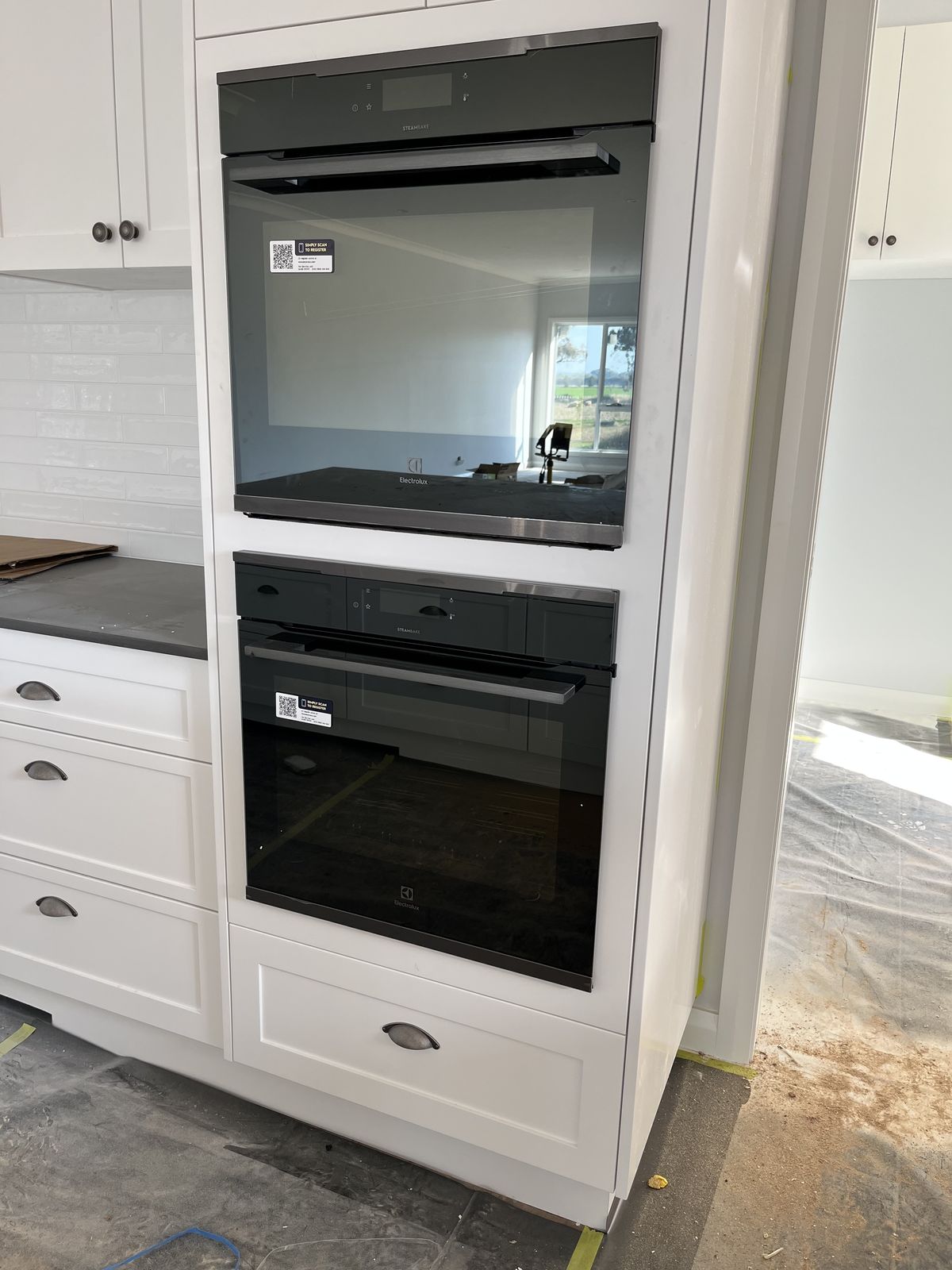 White kitchen with dual wall ovens and a servery window to the outdoors