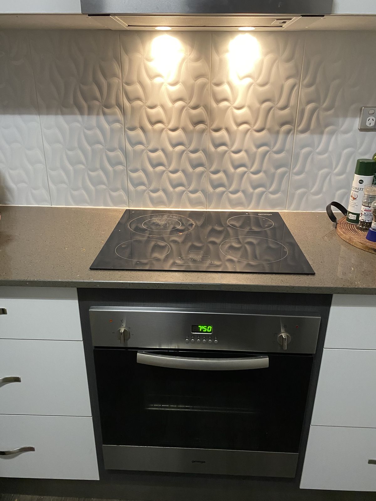 Modern kitchen with a sculptural wave-tile splashback and black appliances