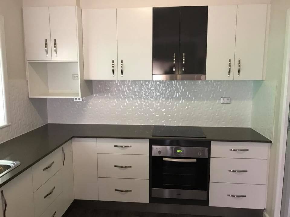 White kitchen with grey stone benchtop and textured splashback