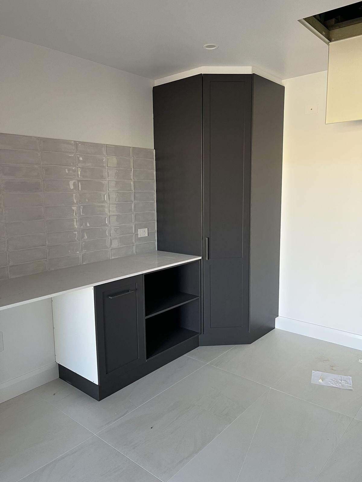 Laundry with white cabinetry, black feature bin drawer and stone top