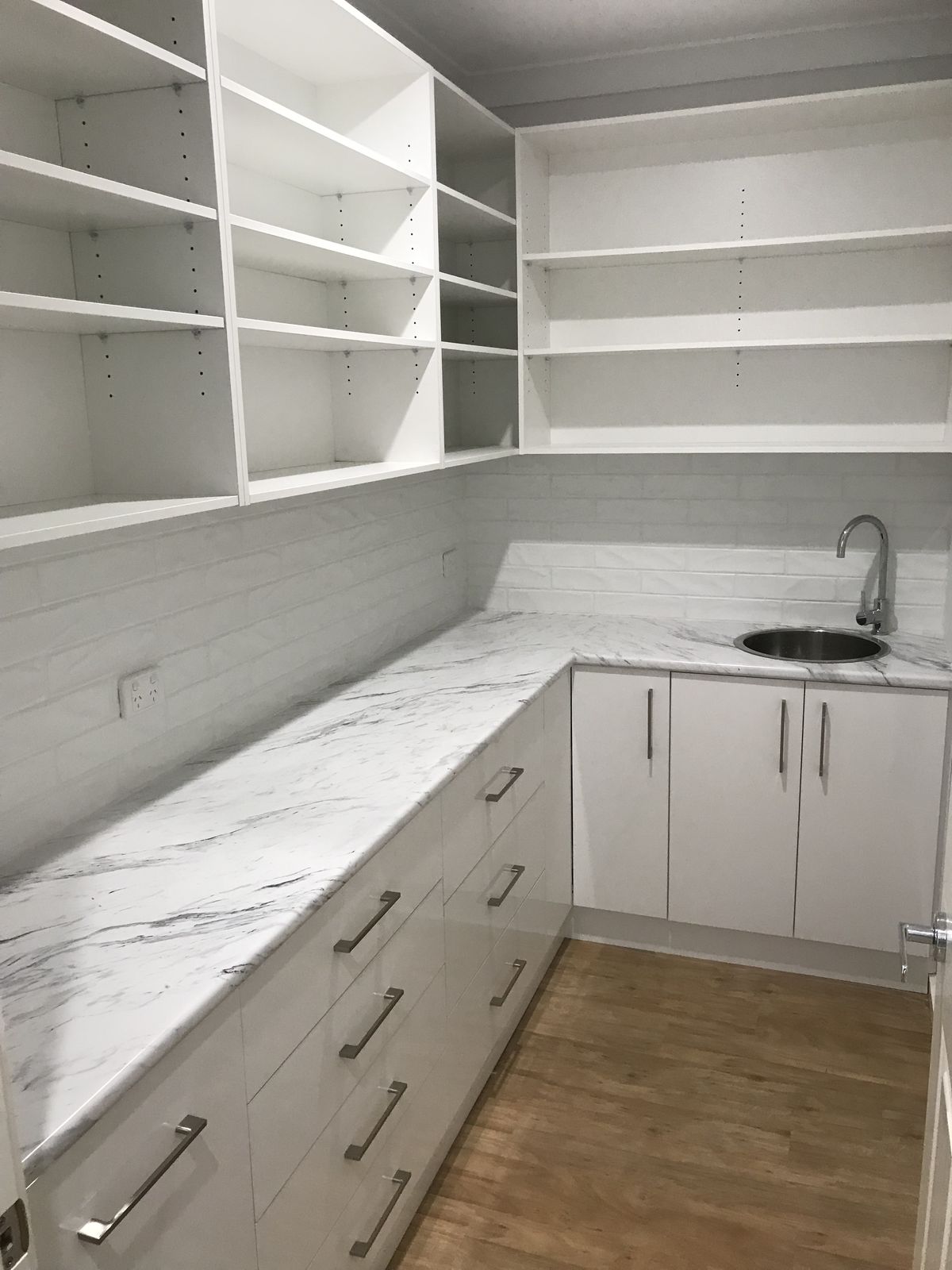 Laundry with marble-look benchtops, open shelving and timber accents