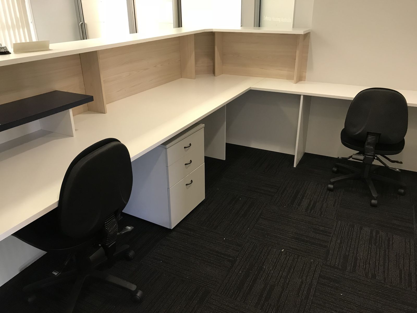 Custom office desk run in pale timber with drawer units