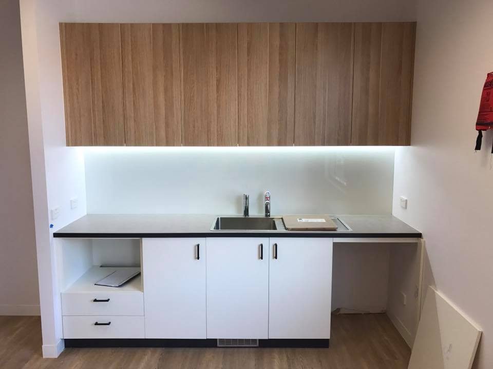 Office kitchenette with timber upper cabinets, LED lighting and white base units