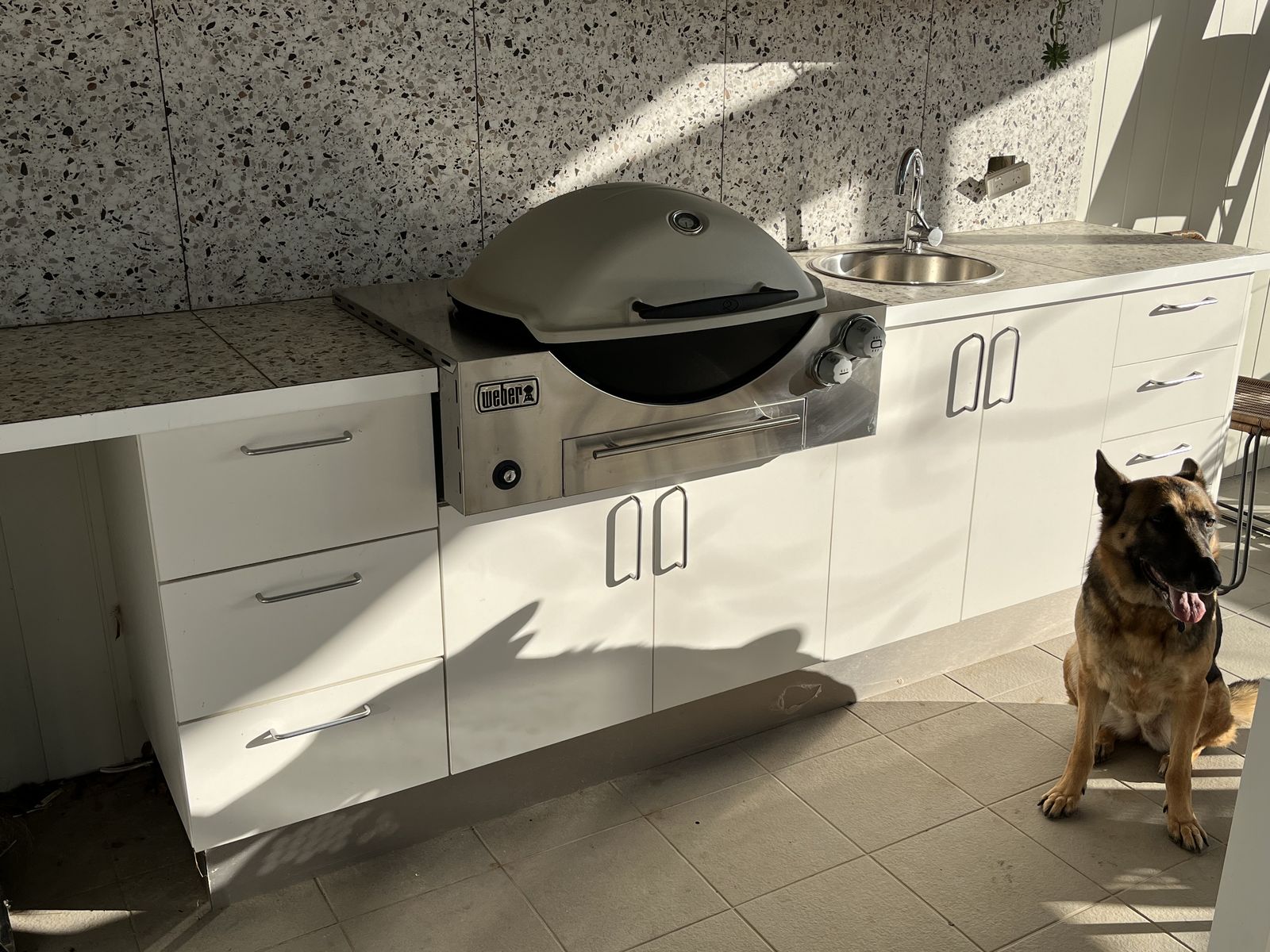 White outdoor BBQ kitchen with stainless barbecue and drawers