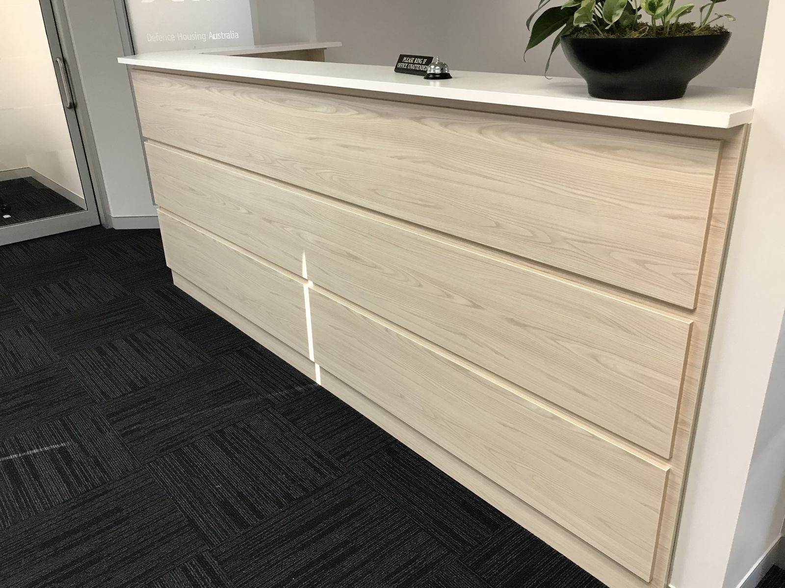 Long pale-timber reception desk with white counter