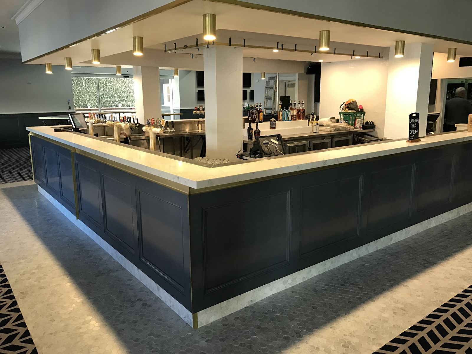 Commercial bar fit-out with navy cabinetry, stone top and feature lighting