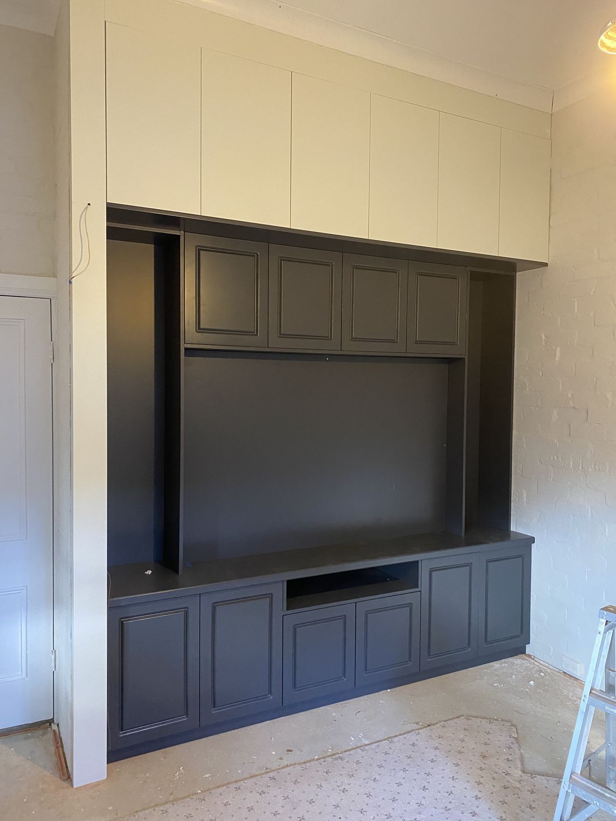 Custom entertainment wall unit with dark cabinetry and floating shelves