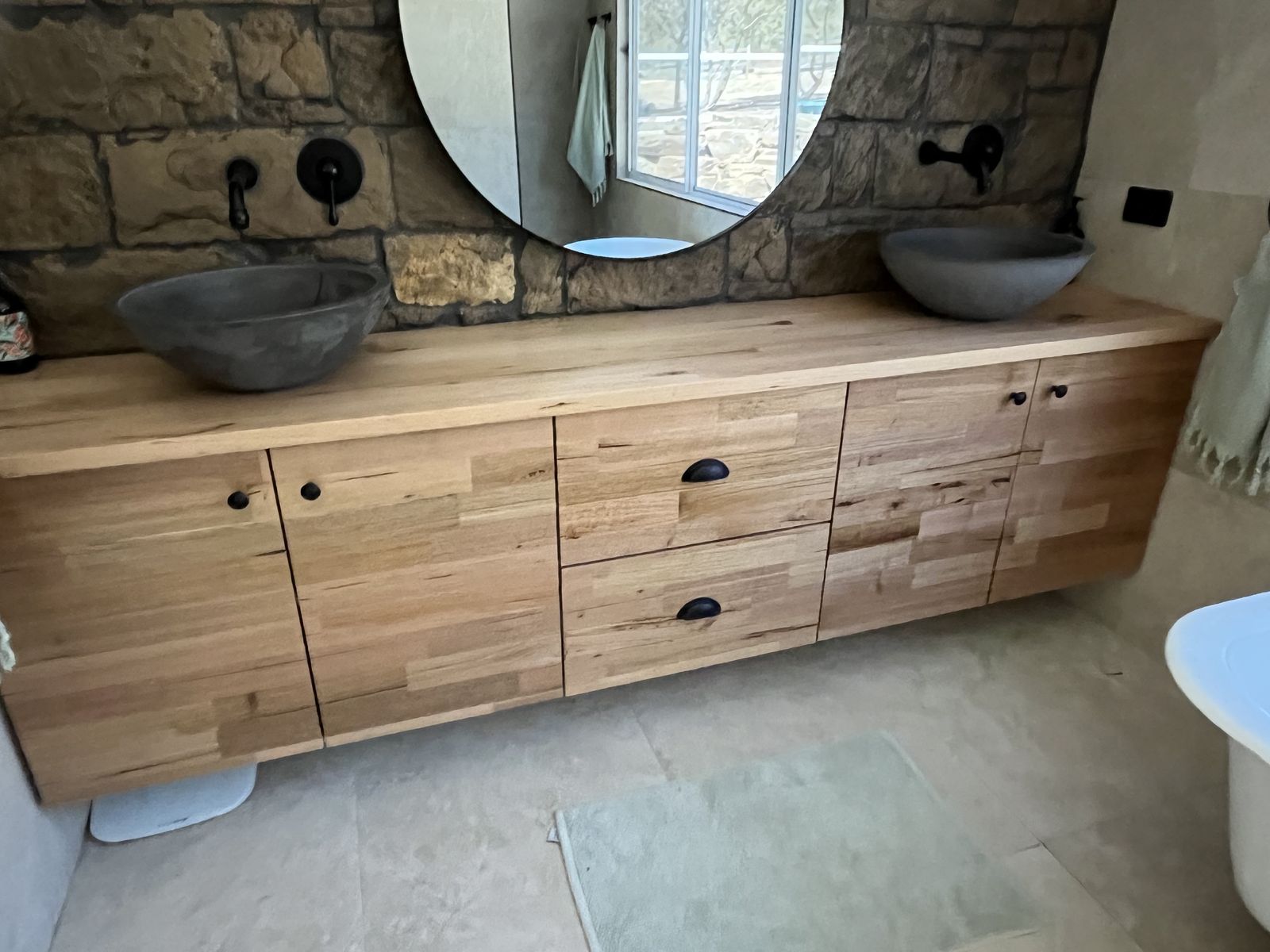 Long timber vanity with two undermount basins and stone-look tile backdrop