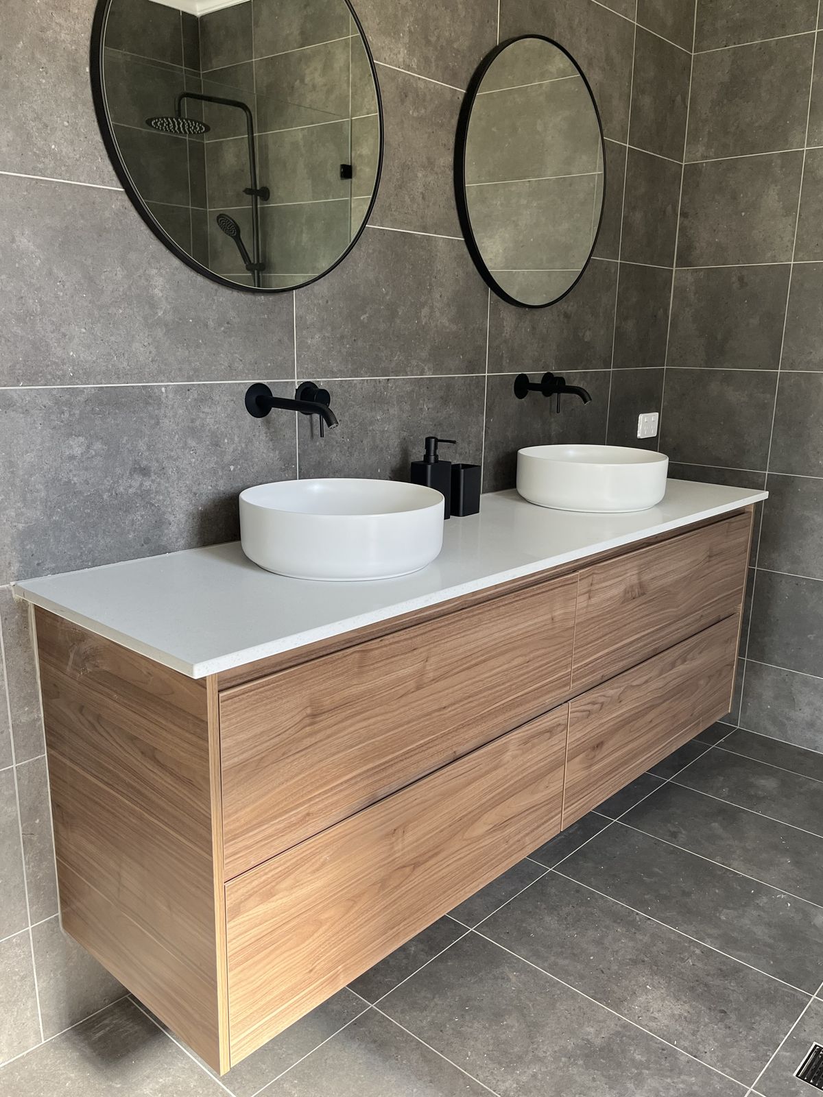 Floating timber vanity with double basins and round black-framed mirrors