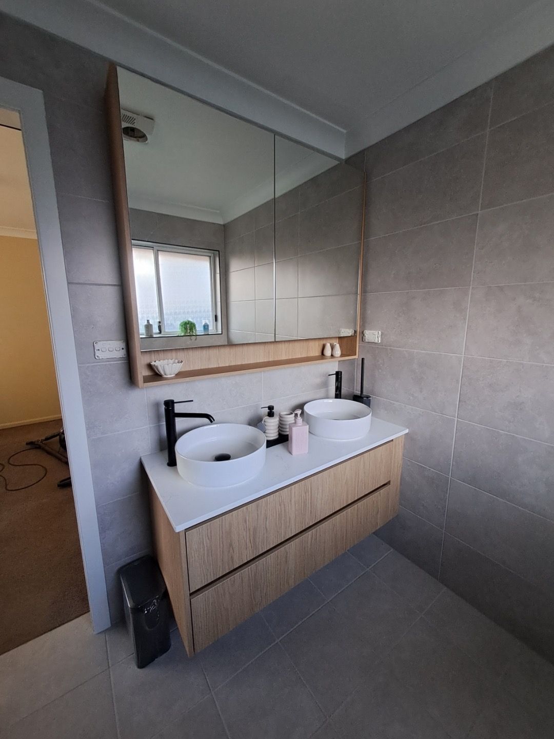Floating timber vanity with double basins against large grey tiles